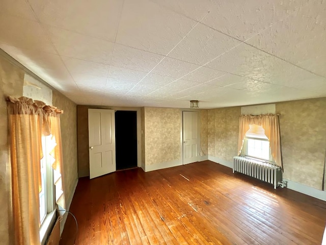 empty room with hardwood / wood-style flooring, baseboards, and radiator