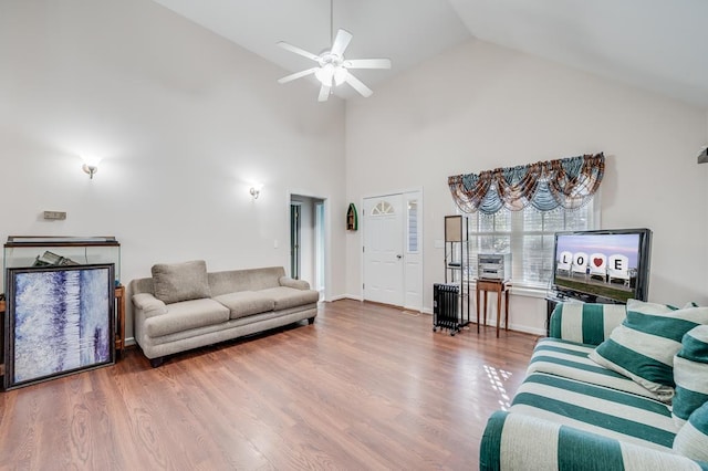 living room featuring high vaulted ceiling, a ceiling fan, baseboards, and wood finished floors