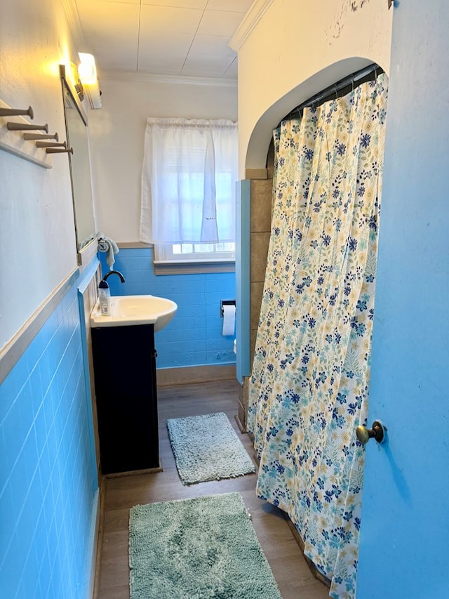 6136 Maddox Blvd, Chincoteague, VA 23336 - bathroom with vanity, wood finished floors, a wainscoted wall, ornamental molding, and tile walls