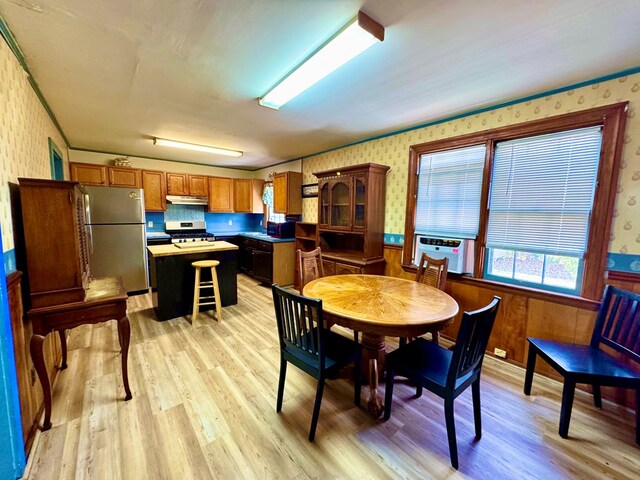 6136 Maddox Blvd, Chincoteague, VA 23336 - dining space with wainscoting, cooling unit, wallpapered walls, and light wood-style floors