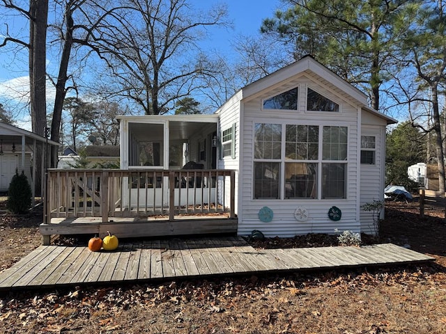 rear view of house with a wooden deck and a sunroom