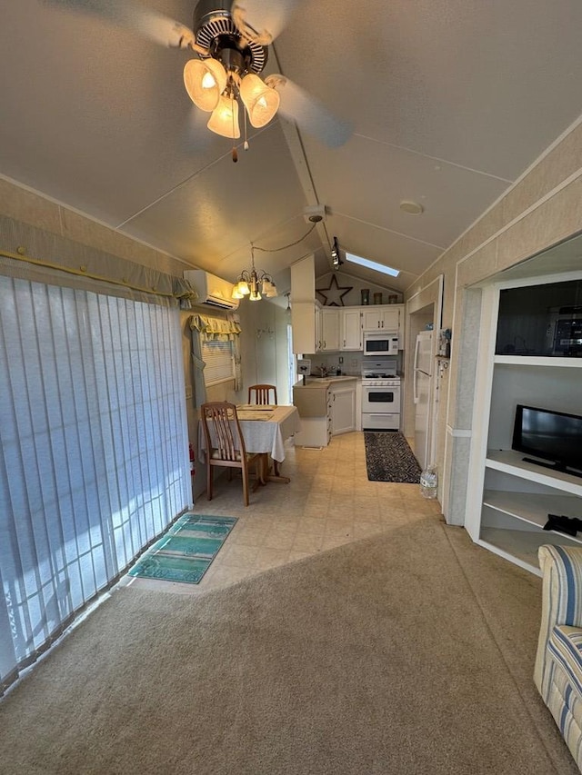 interior space featuring an AC wall unit, lofted ceiling, white appliances, white cabinets, and ceiling fan with notable chandelier