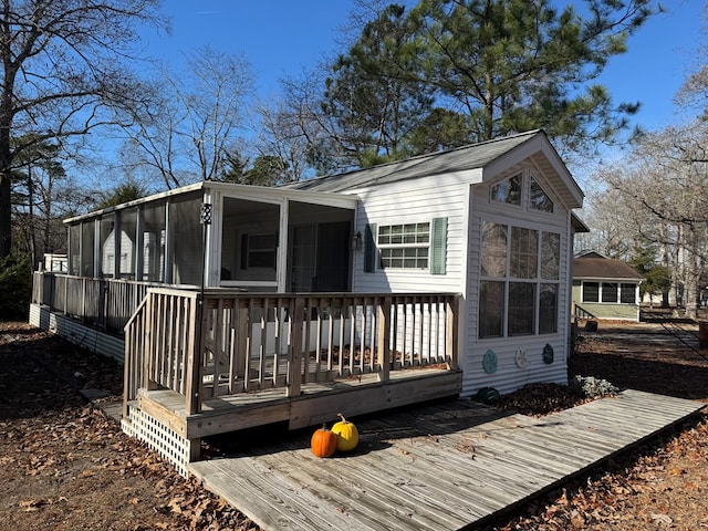 rear view of property featuring a wooden deck and a sunroom