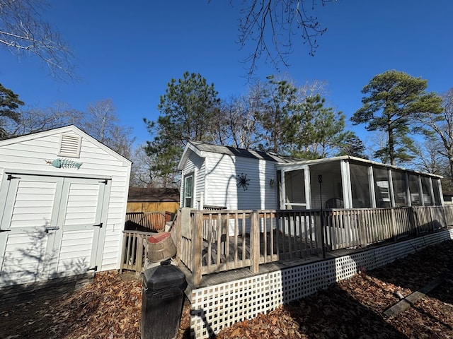 rear view of house with a deck, a storage shed, and a sunroom