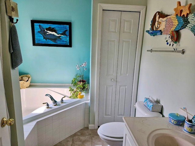 bathroom featuring tile patterned floors, vanity, toilet, and tiled bath