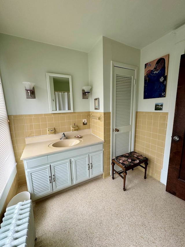 bathroom with radiator heating unit, vanity, and tile walls