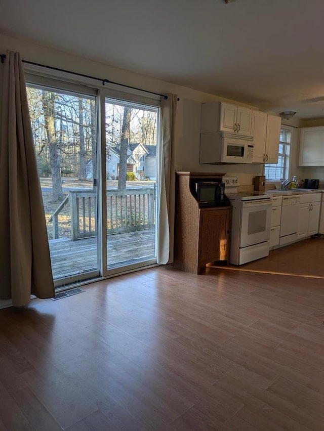 kitchen with sink, white appliances, white cabinets, and hardwood / wood-style flooring