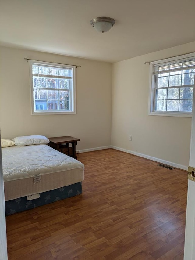 bedroom featuring multiple windows and dark hardwood / wood-style flooring