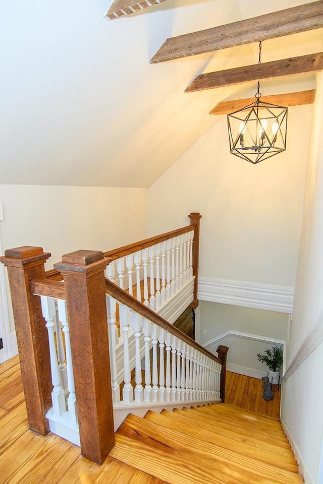 staircase featuring wood-type flooring, lofted ceiling, and a notable chandelier