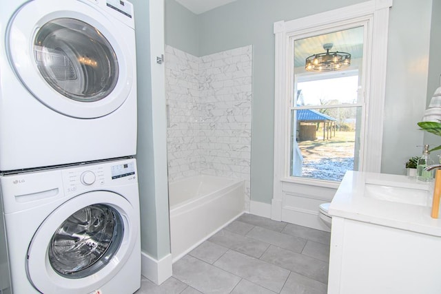 washroom featuring plenty of natural light, light tile patterned floors, stacked washing maching and dryer, and sink