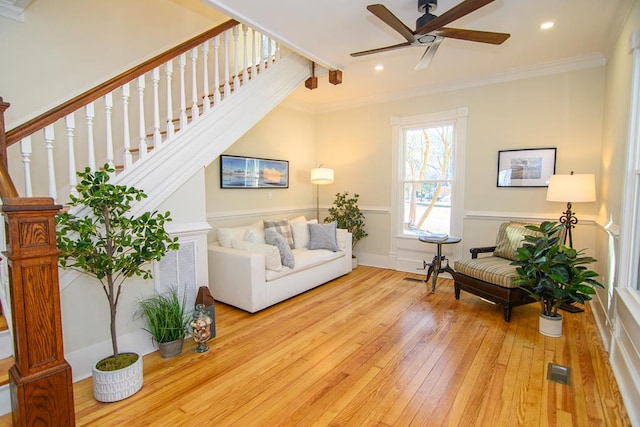 living room featuring ceiling fan, light wood-type flooring, and crown molding