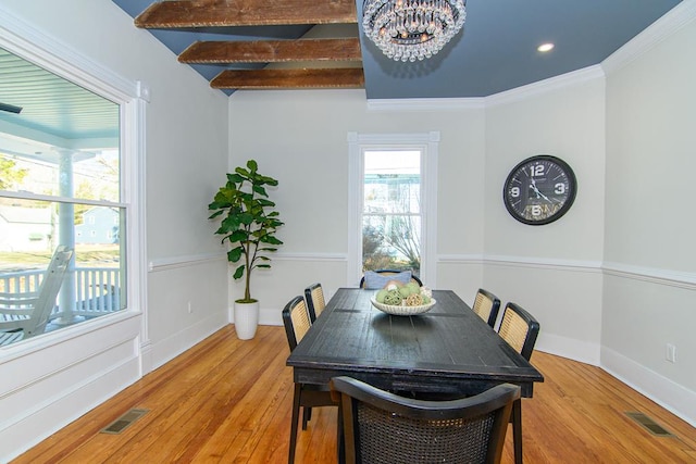 dining space featuring beam ceiling, light wood-type flooring, an inviting chandelier, and crown molding