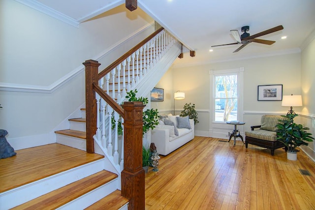 staircase featuring hardwood / wood-style flooring, ceiling fan, and ornamental molding