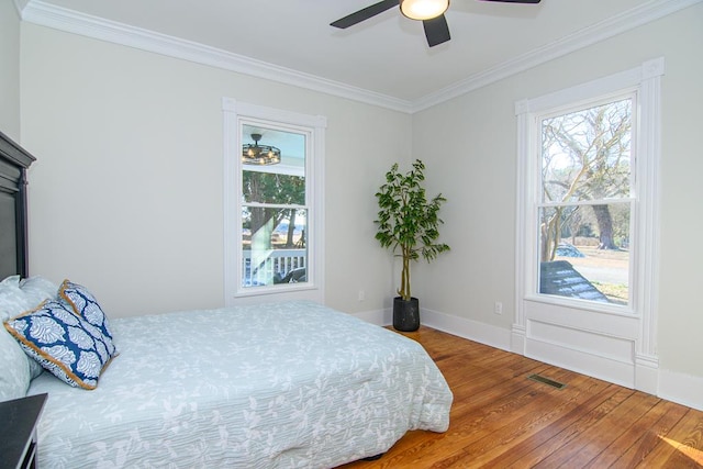 bedroom with hardwood / wood-style flooring, ceiling fan, and ornamental molding