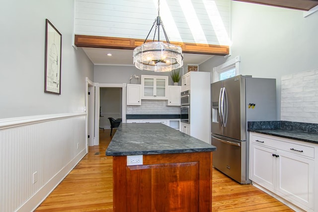 kitchen featuring a center island, white cabinets, light wood-type flooring, decorative light fixtures, and stainless steel fridge with ice dispenser