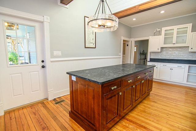 kitchen featuring tasteful backsplash, white cabinets, pendant lighting, a kitchen island, and light wood-type flooring