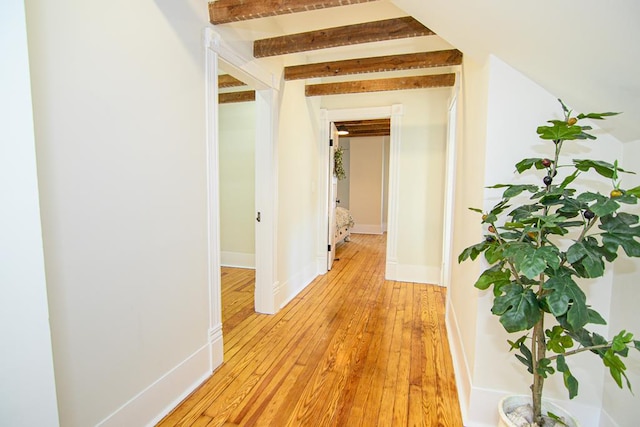 corridor with beam ceiling and light hardwood / wood-style floors