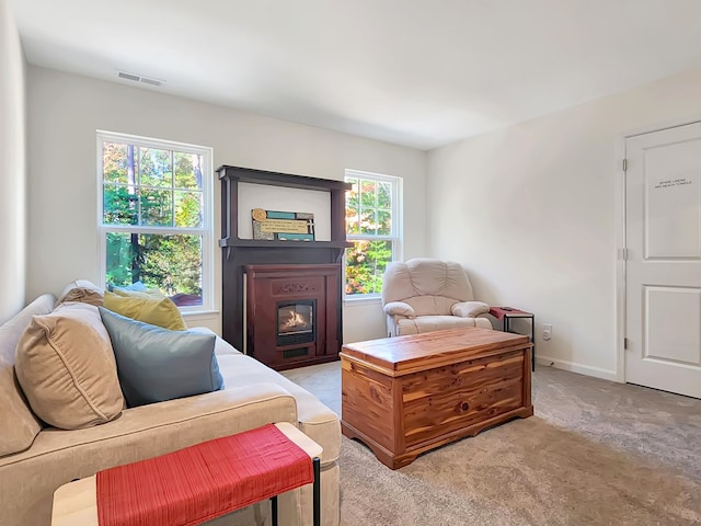 living room with light carpet, a fireplace, and a healthy amount of sunlight