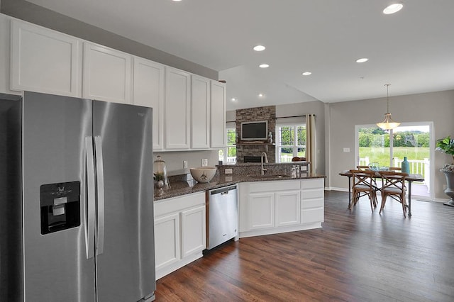 kitchen with hanging light fixtures, sink, dark stone countertops, appliances with stainless steel finishes, and white cabinetry