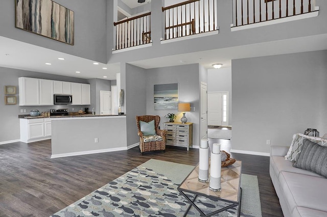 living room with a towering ceiling and dark hardwood / wood-style floors