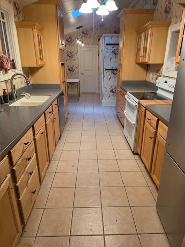 12 Justis St, Onancock, VA 23417 - kitchen featuring wallpapered walls, appliances with stainless steel finishes, light tile patterned floors, a sink, and a ceiling fan