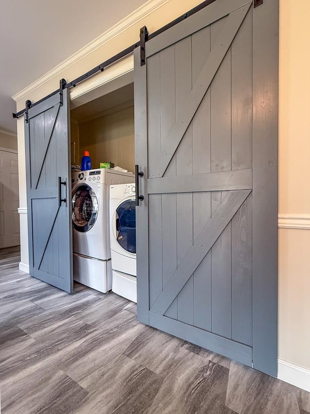 clothes washing area featuring laundry area, a barn door, separate washer and dryer, and crown molding