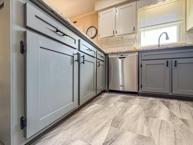 kitchen with gray cabinets, stone counters, backsplash, a sink, and stainless steel dishwasher