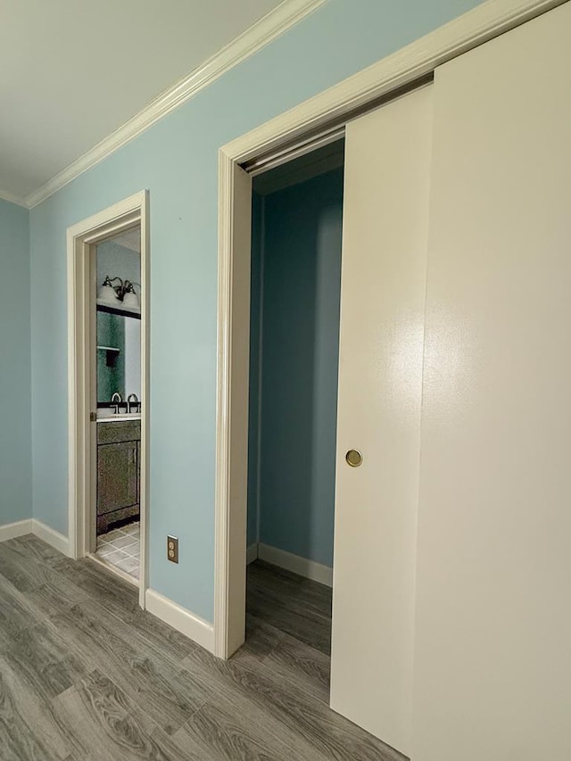 corridor featuring baseboards, wood finished floors, and crown molding