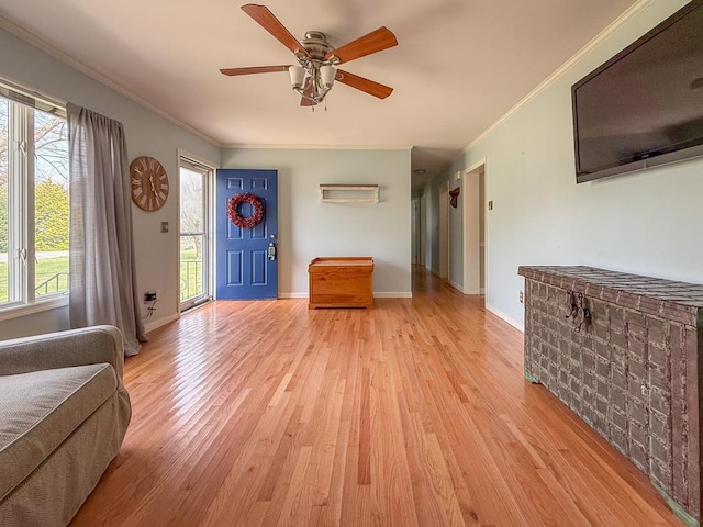 foyer entrance featuring light wood finished floors, baseboards, crown molding, and a ceiling fan