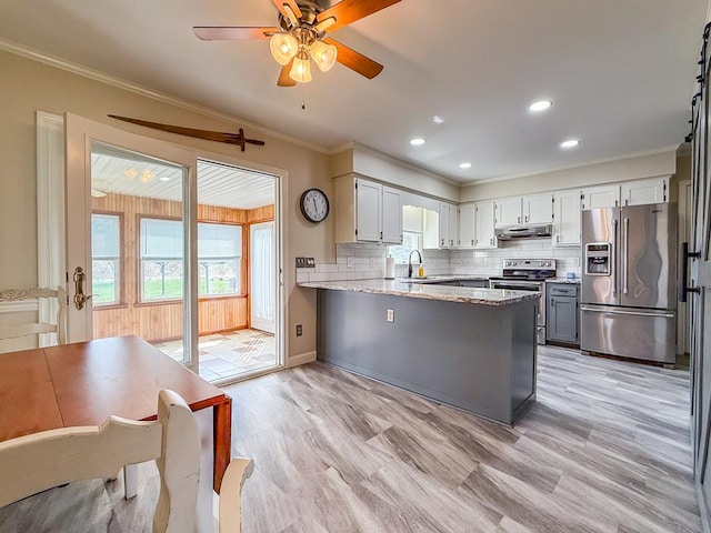 kitchen featuring decorative backsplash, ornamental molding, stainless steel appliances, and a peninsula