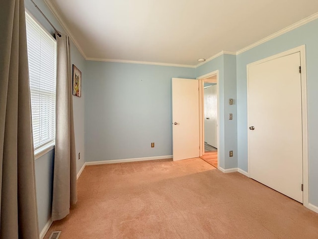 unfurnished bedroom featuring light carpet, crown molding, and baseboards