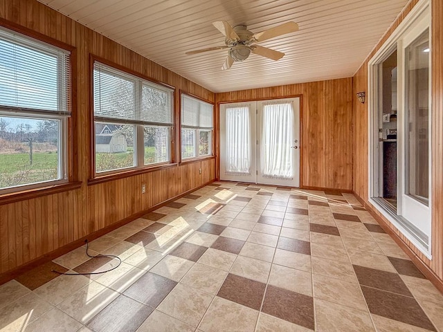 unfurnished sunroom featuring baseboards, wooden walls, and wooden ceiling