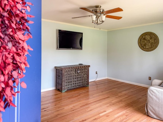 living area featuring crown molding, baseboards, and wood finished floors