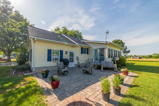 rear view of house with a lawn, a patio area, and roof with shingles