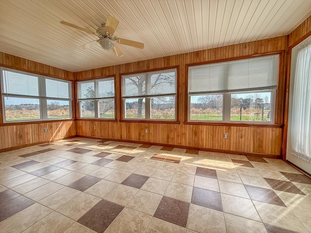 unfurnished sunroom featuring wooden ceiling, wooden walls, and plenty of natural light