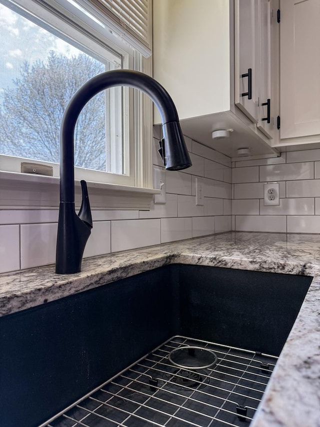 interior details with tasteful backsplash, light stone counters, and white cabinets