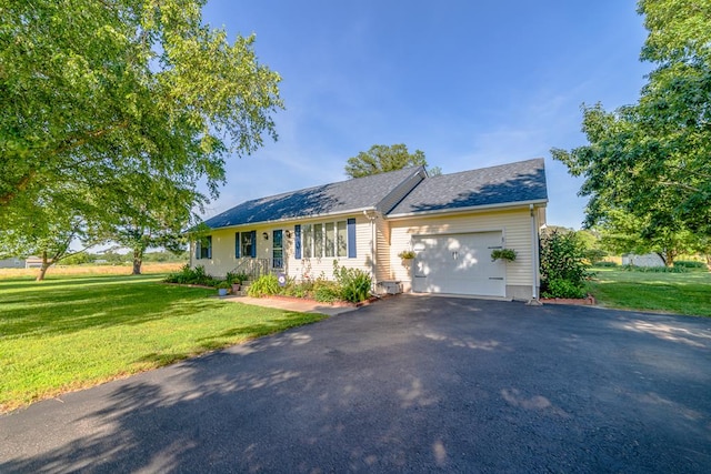 ranch-style home with driveway, an attached garage, a front lawn, and roof with shingles