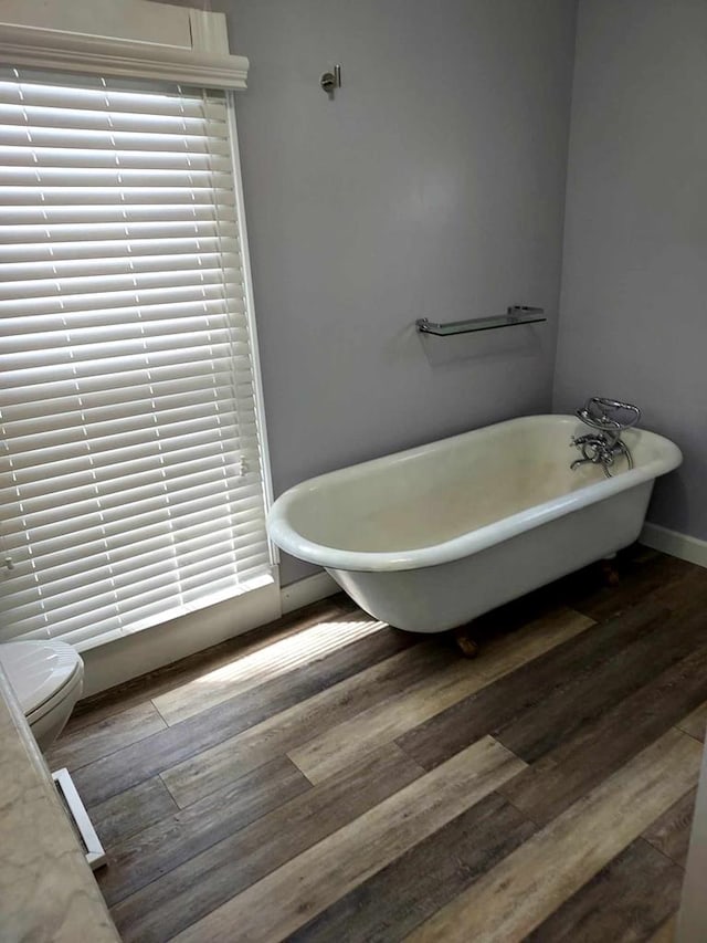 bathroom featuring toilet, a bath, and hardwood / wood-style flooring