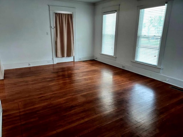 unfurnished room featuring a healthy amount of sunlight and dark hardwood / wood-style floors