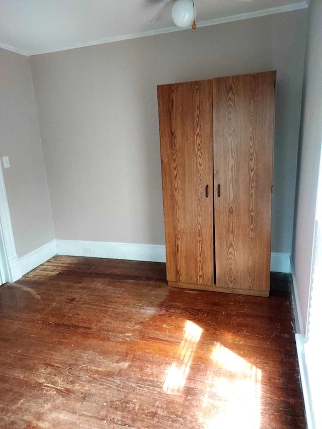 unfurnished bedroom featuring dark hardwood / wood-style floors, ceiling fan, and crown molding