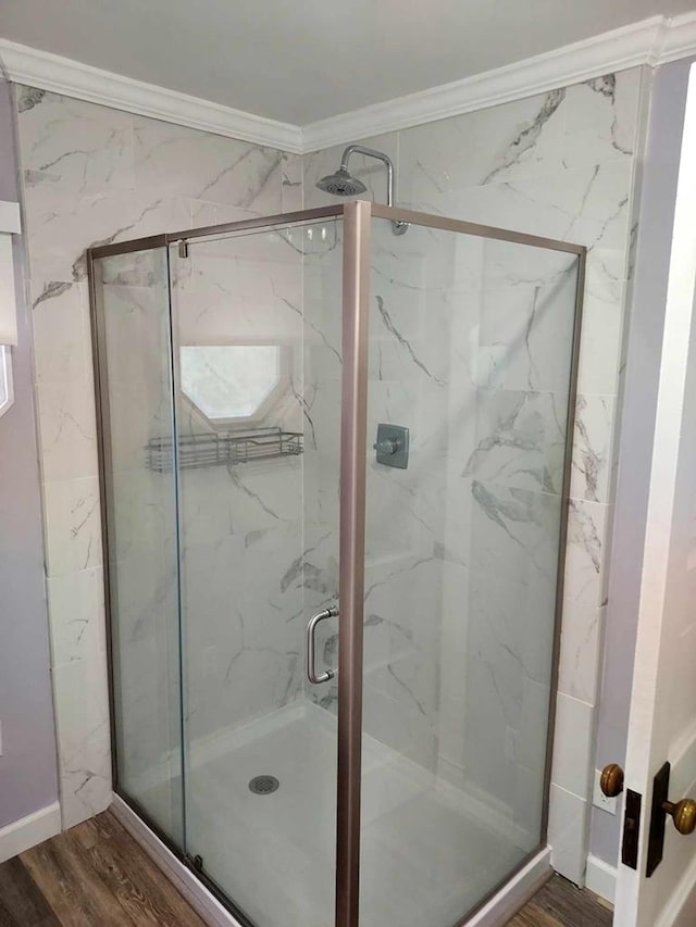 bathroom with crown molding, wood-type flooring, and a shower with shower door