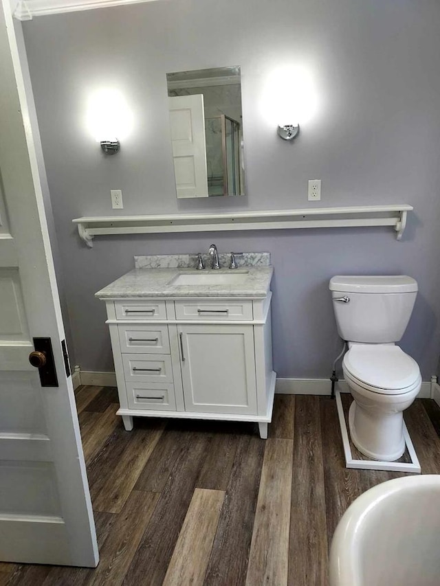 bathroom with hardwood / wood-style floors, vanity, toilet, and an enclosed shower