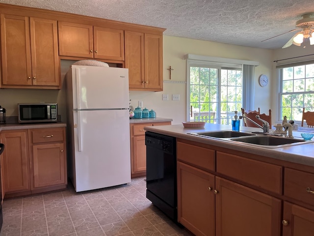 kitchen with a sink, a ceiling fan, black dishwasher, freestanding refrigerator, and stainless steel microwave