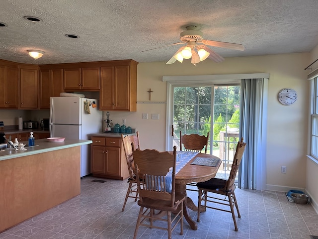 dining room featuring a ceiling fan, a textured ceiling, and baseboards