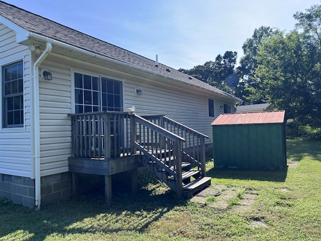 back of house featuring a storage shed, a shingled roof, a lawn, and an outdoor structure