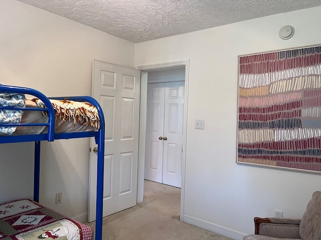 bedroom with carpet flooring, a textured ceiling, and baseboards