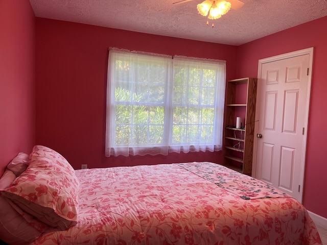 bedroom with ceiling fan and a textured ceiling