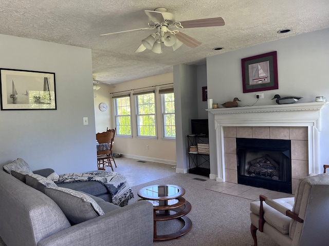living area featuring a textured ceiling, ceiling fan, a fireplace, visible vents, and baseboards