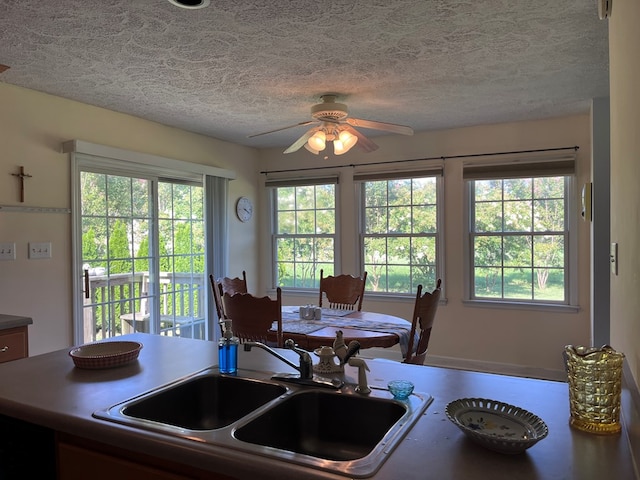 kitchen featuring a textured ceiling, ceiling fan, a sink, and a wealth of natural light