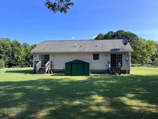 back of property featuring a storage shed, roof with shingles, a lawn, and an outbuilding